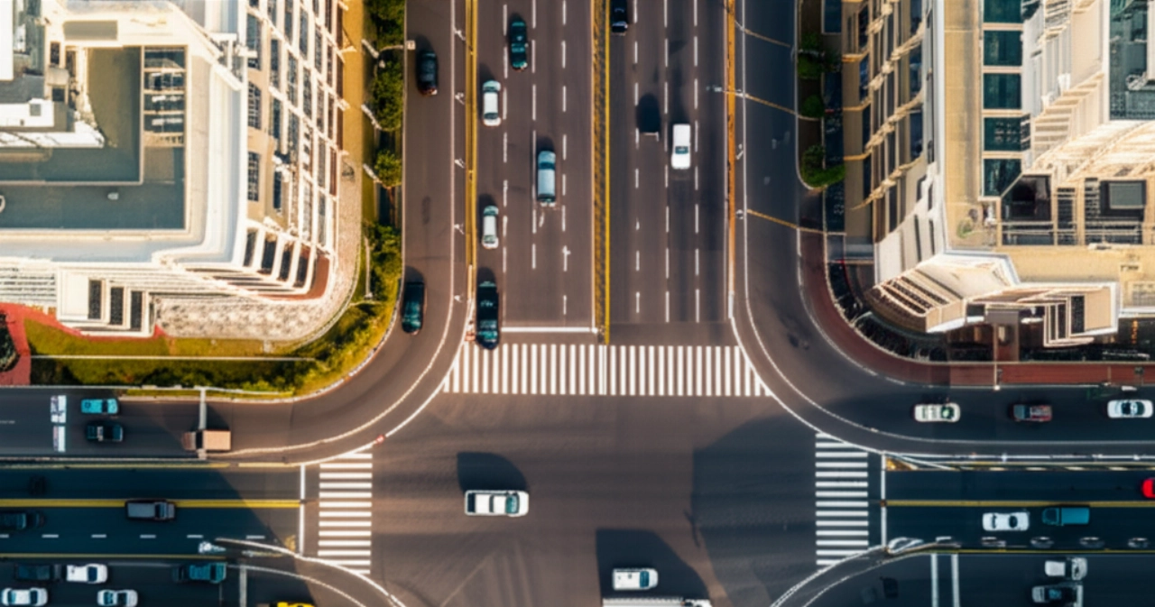 Vista aerea iperrealistica di un nodo logistico urbano con un agile taxi merci che si muove nel traffico e un furgone a noleggio più lento.